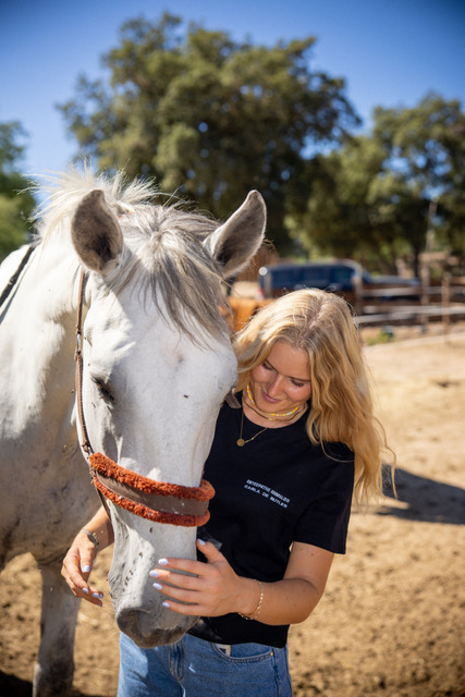Carla avec un cheval blanc et gris dans un manège