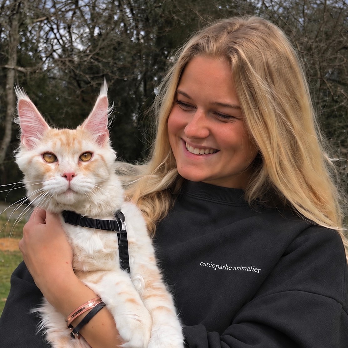 Carla souriante, un grand chat crème dans les bras